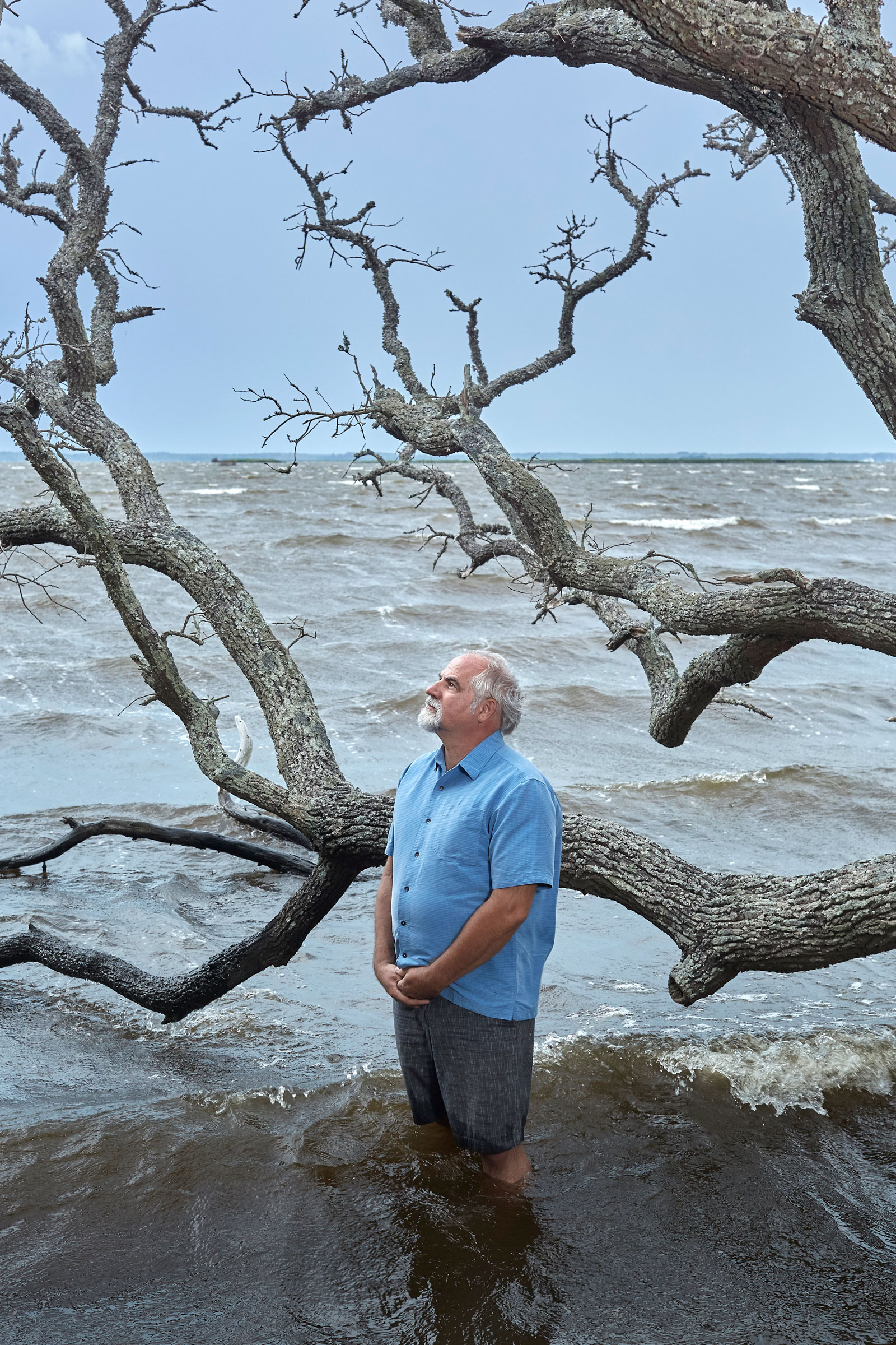 Robbie Fearn, center director at Pine Island, stands beside a live oak that was killed by saltwater intrusion from rising seas. Justin Cook