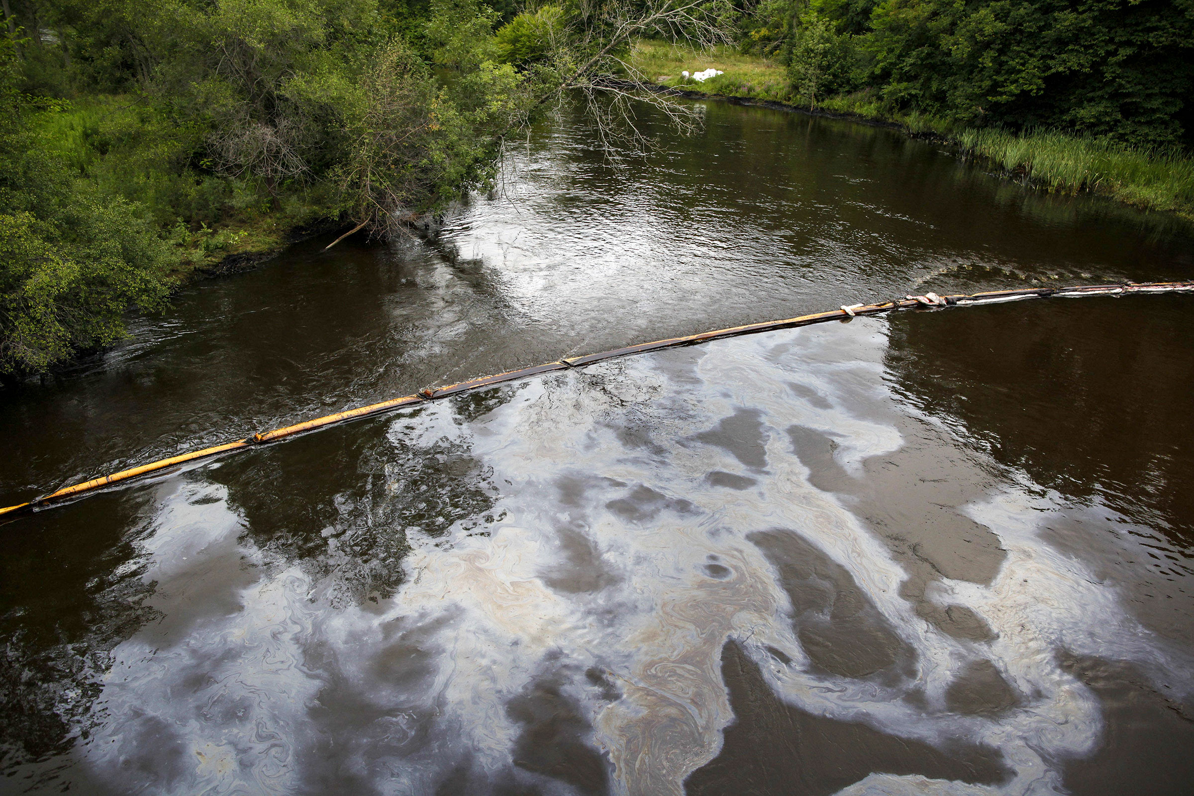 A boom traps oil as it flows down the Kalamazoo River in Michigan, July, 2010, where over 1.2 million gallons of tar sands crude oil were spilled from an Enbridge pipeline. Brian Kersey/UPI/Alamy